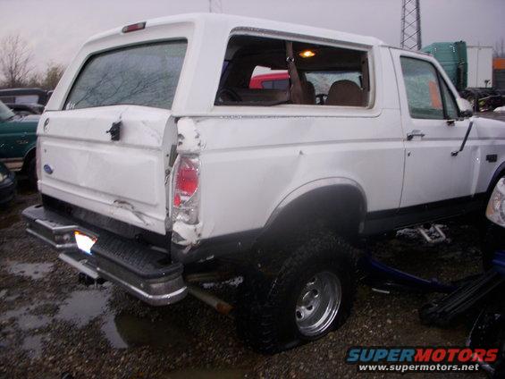 White 1995 Ford Bronco rear view with damage to the tailgate and rear quarter panel