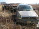 1990 Ford Bronco - Two pickup trucks are stuck in the mud in a field with dry grass and sparse trees.