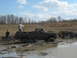 1990 Ford Bronco - A pickup truck is stuck deep in the mud with two people standing around it.