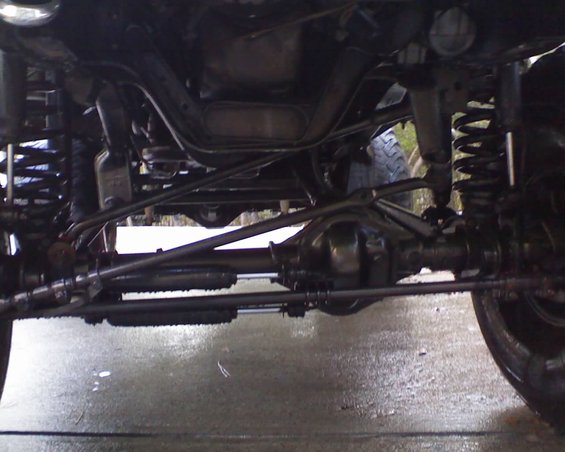 Undercarriage of a vehicle with visible suspension components, steering linkage, and differential