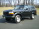 1996 Ford Bronco - This black 1996 Ford Bronco is shown from a 3/4 front angle, aftermarket wheels and running boards.