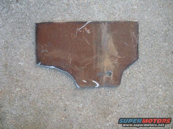 Brown metal bracket with a hole, lying on concrete