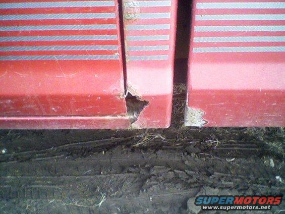 red truck door seam with rust damage and horizontal silver stripes