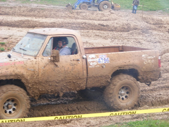Mud-covered pickup truck with number 4796 on door, driving through mud