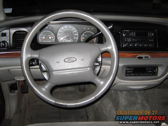 Interior dashboard of a 1997 Ford Crown Victoria with a gray steering wheel and wood trim
