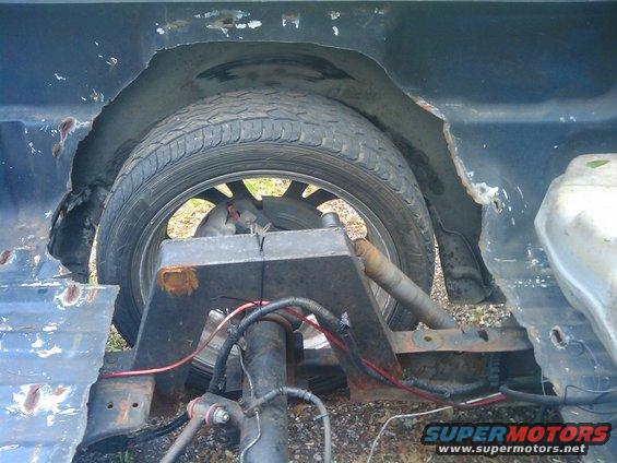 Rear wheel well showing rust damage and suspension components