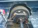 2000 Ford F-150 - The rear wheel well of a dark blue truck shows significant rust and damage to the body panels.