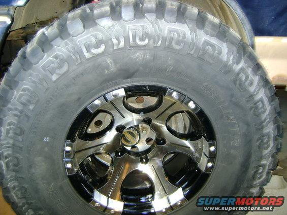 Close-up of a large off-road tire with aggressive tread and a chrome and black rim