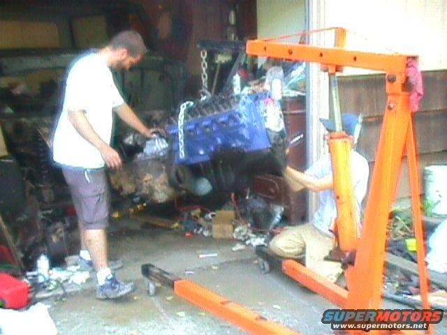 Engine being lifted into vehicle bay with an engine hoist