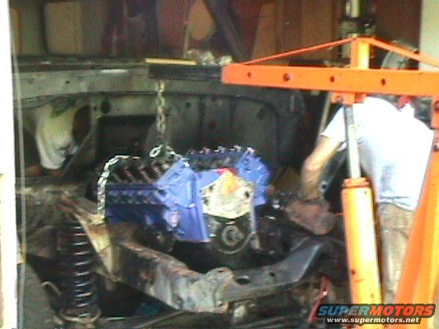 engine being lowered into vehicle bay with an engine hoist