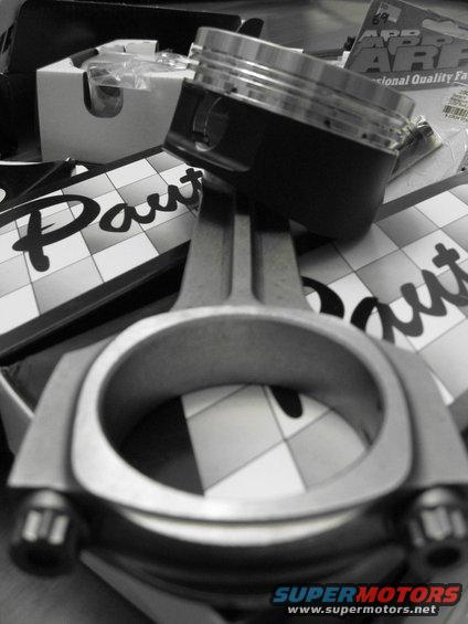 Piston and connecting rod on checkered background with 'Paut' text