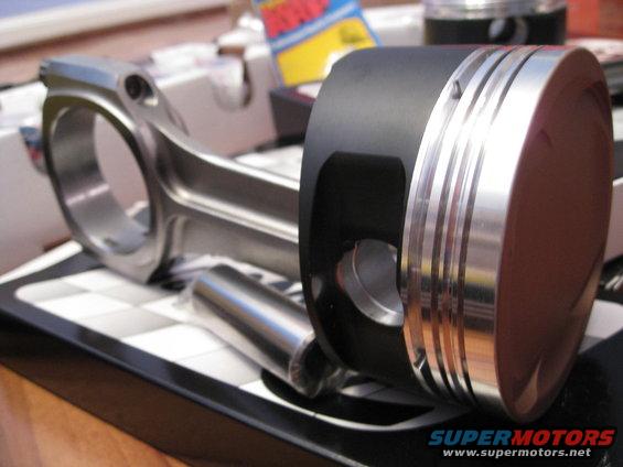 Piston with three silver rings and a connecting rod with a pin