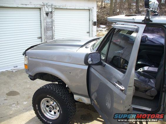 Silver Ford F-150 pickup truck with aftermarket wheels and tires, driver's door open