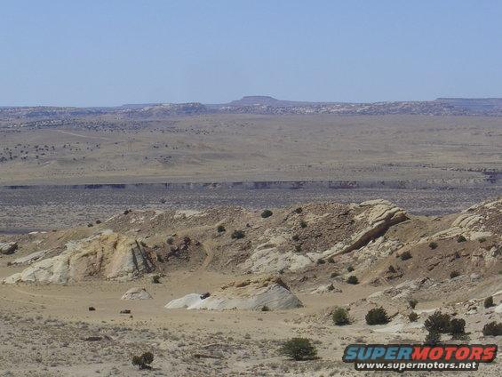 SUV driving on rocky desert terrain under a clear blue sky