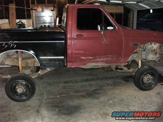1992 Ford F-250 truck chassis with black bed and red cab, missing front wheels