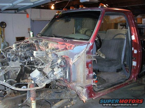 Red pickup truck with front end disassembled, engine compartment exposed, interior visible