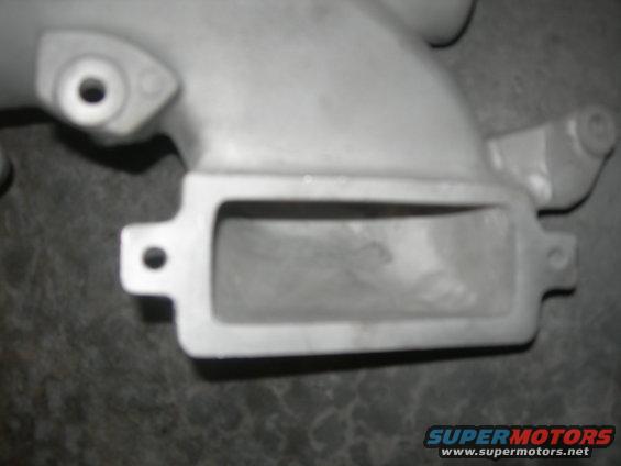 Close-up of a metal intake manifold part with a rectangular opening