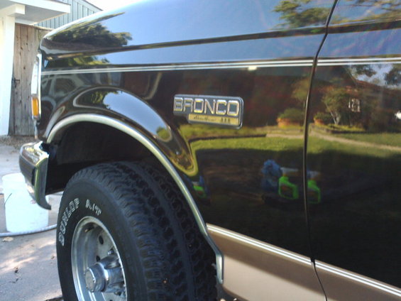 Black 1994 Ford Bronco with tan lower trim, seen from the front quarter angle. The "BRONCO" badge is visible