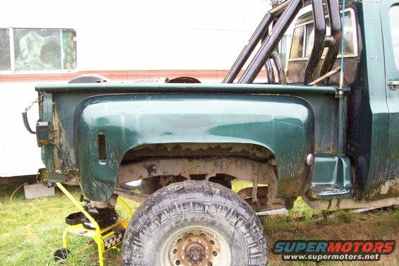 Green pickup truck bed and rear fender with roll bar, seen from the side