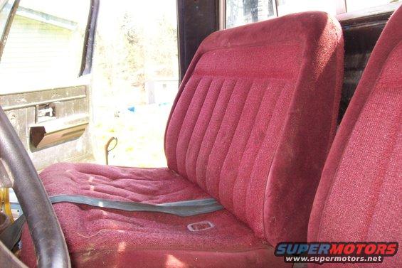 Red velour bench seat and door panel inside a truck cab, with a steering wheel visible