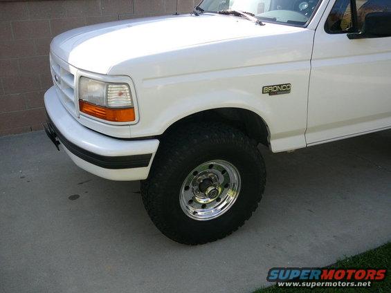 White Ford Bronco parked on concrete, showing front fender and wheel