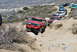 1996 Ford Bronco - Several SUVs, including a red Ford Bronco, are off-roading on a steep, rocky path.