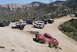 1996 Ford Bronco - Several Ford Broncos are gathered on a dusty, off-road trail in a mountainous area.