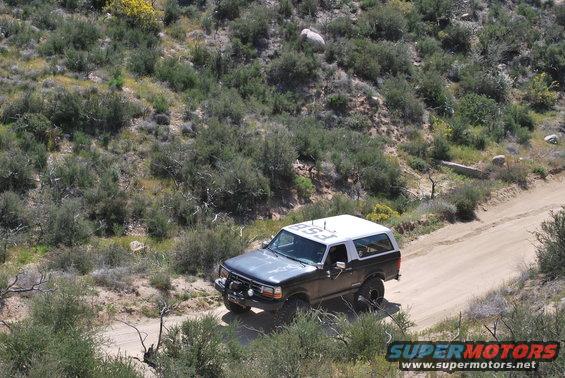 Gray 1996 Ford Bronco with white roof driving on a dirt road