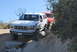 1996 Ford Bronco - A white 1996 Ford Bronco tackles an off-road obstacle course, followed closely by another vehicle.