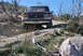 1996 Ford Bronco - A maroon and white Ford Bronco navigates a rocky, off-road trail under a clear blue sky.