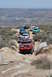 1996 Ford Bronco - A line of off-road vehicles navigates a rocky mountain trail under a clear sky.