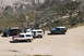 1996 Ford Bronco - Several SUVs and trucks, including a 1996 Ford Bronco, are gathered on a dusty mountain road.