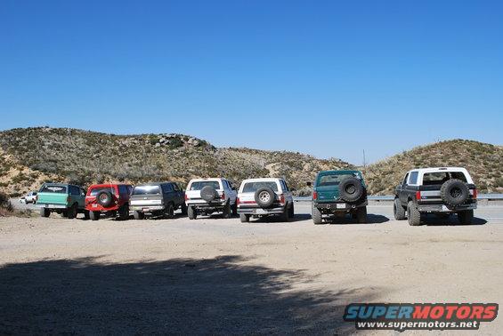 Several Ford Bronco SUVs parked on a dirt lot, viewed from the rear