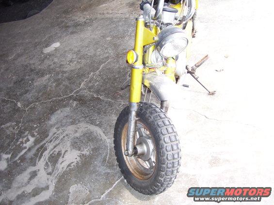 Yellow motorcycle front wheel and fender, parked on concrete