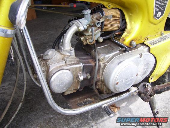 Yellow 1972 Honda CT70 engine and frame detail, showing carburetor and air filter