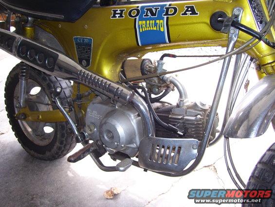 Gold Honda CT70 Trail motorcycle, side view showing engine and exhaust