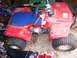 1984 Honda TRX 90 - A red and blue Honda 70 Fourtrax ATV is parked indoors, surrounded by other items.
