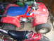 1984 Honda TRX 90 - This red ATV, identified as a '70 Fourtrax, is parked indoors with other vehicles.