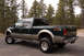 2003 Ford F-350 - The 2003 Ford F-350 pickup truck is viewed from a three-quarter front angle, with a wooded area behind it.