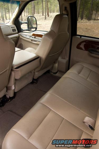 Interior of a truck, showing tan leather seats and the center console. Trees are visible through the windows