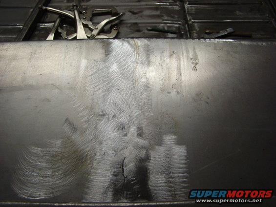 Metal panel with welding clamps and grinder marks