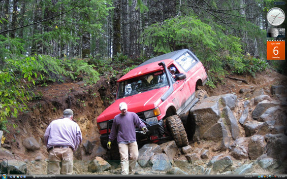 Red off-road SUV with snorkel and large tires navigating a rocky incline