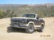 1986 Ford Bronco - 1986 Ford Bronco parked on a dirt trail with mountainous terrain behind it.