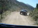 1986 Ford Bronco - 1986 Ford Bronco navigates a winding dirt path in a mountainous, arid landscape.
