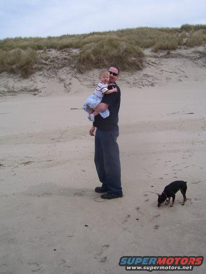 Man holding child, dog on beach
