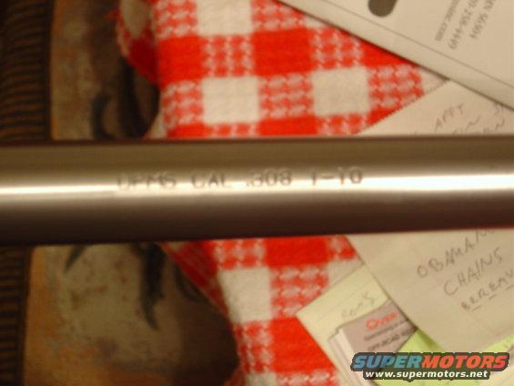 Metal pipe with engraved text 'UPMS CAL .308 1-10' rests on a red and white checkered cloth