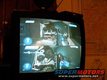 Split-screen video game displayed on a television, showing vehicles in a digital environment