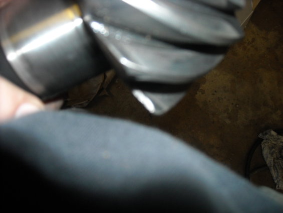 Close-up of metallic gear teeth with a hand in the foreground
