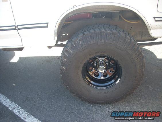 White SUV with large off-road tire and black steel wheel, side view
