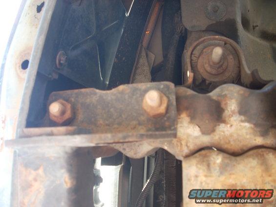 rusted metal bracket with bolts, part of a vehicle's undercarriage